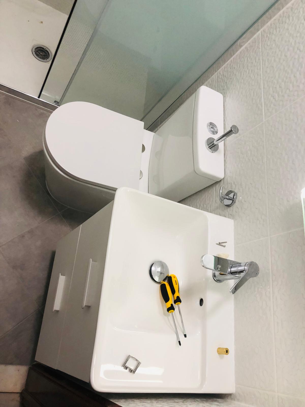 Pia e vaso sanitário do banheiro com azulejos brancos texturizados